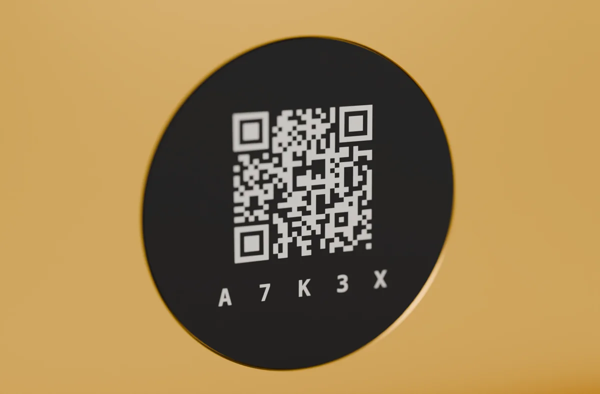 Nahaufnahme: schwarzes NFC-Etikett mit gelasertem QR-Code und Gerätecode, bündig in der goldenen Platte